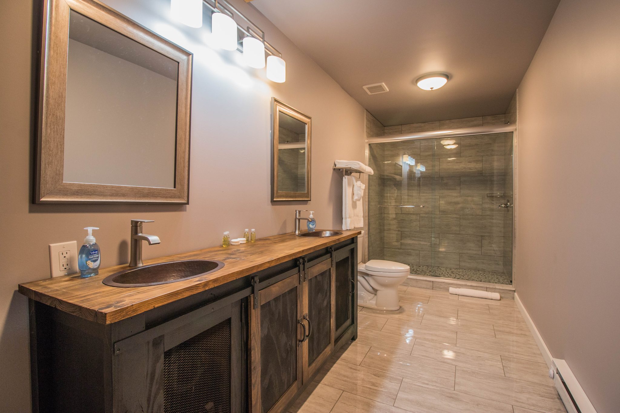 A tower suite bathroom with a long double vanity and a walk-in shower