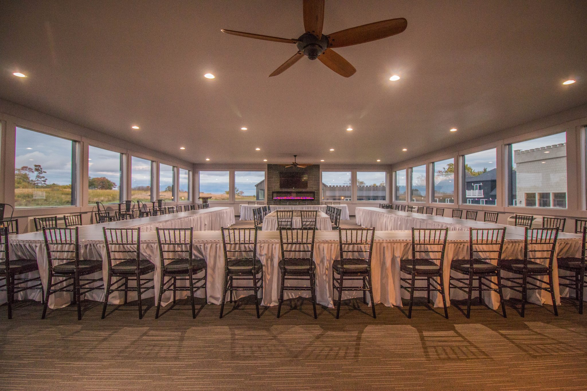 The conference room set up with long draped tables, windows on three sides and a fireplace at the far end