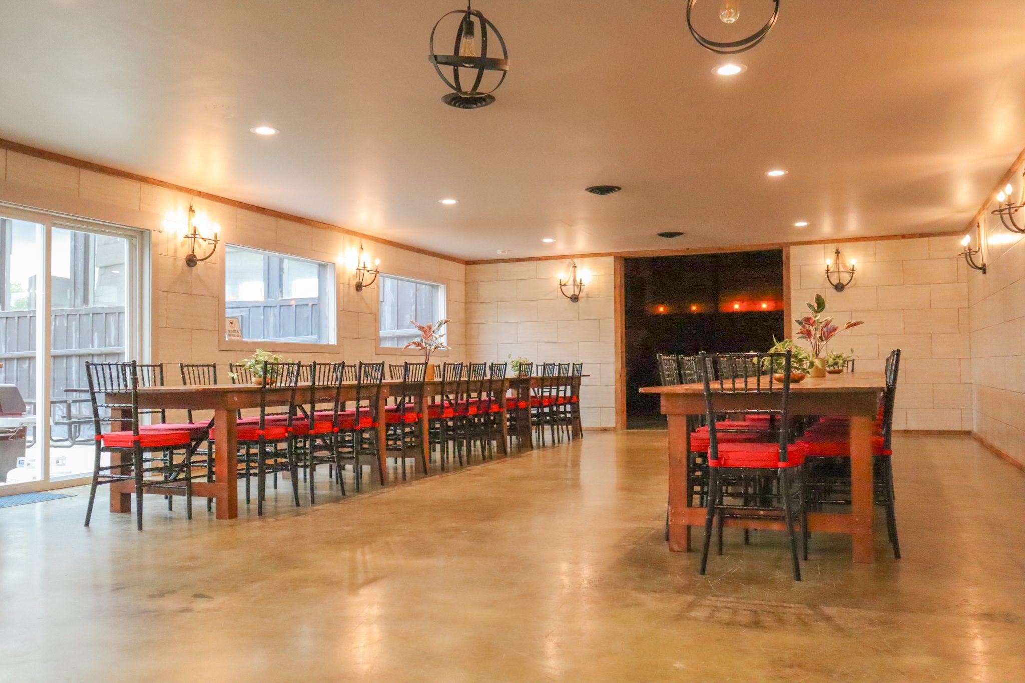 The dining room: long tables with red chairs down a bright room with wall sconces
