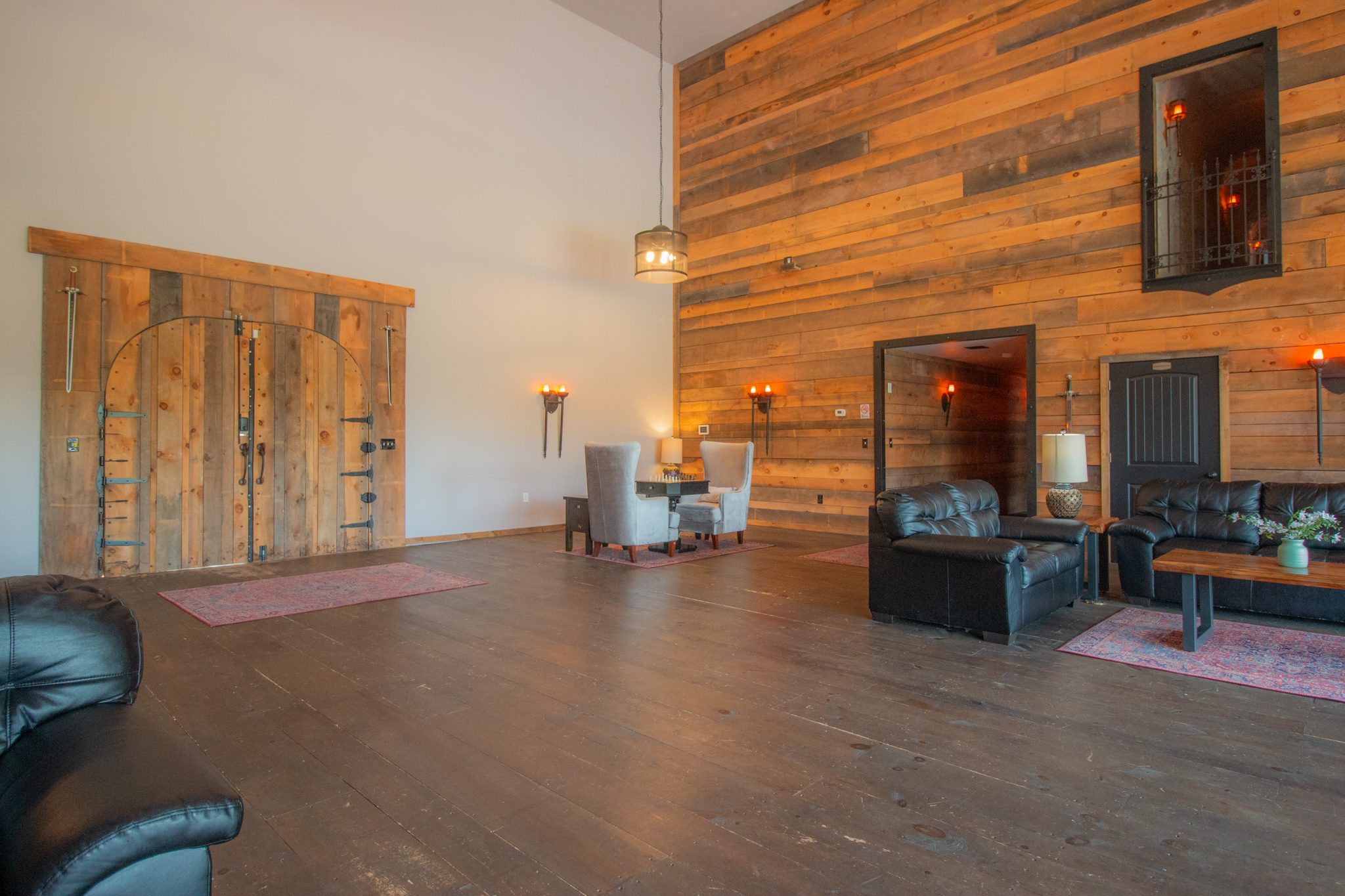 The foyer the other way: a tall timber wall, sliding barn doors and leather sofas