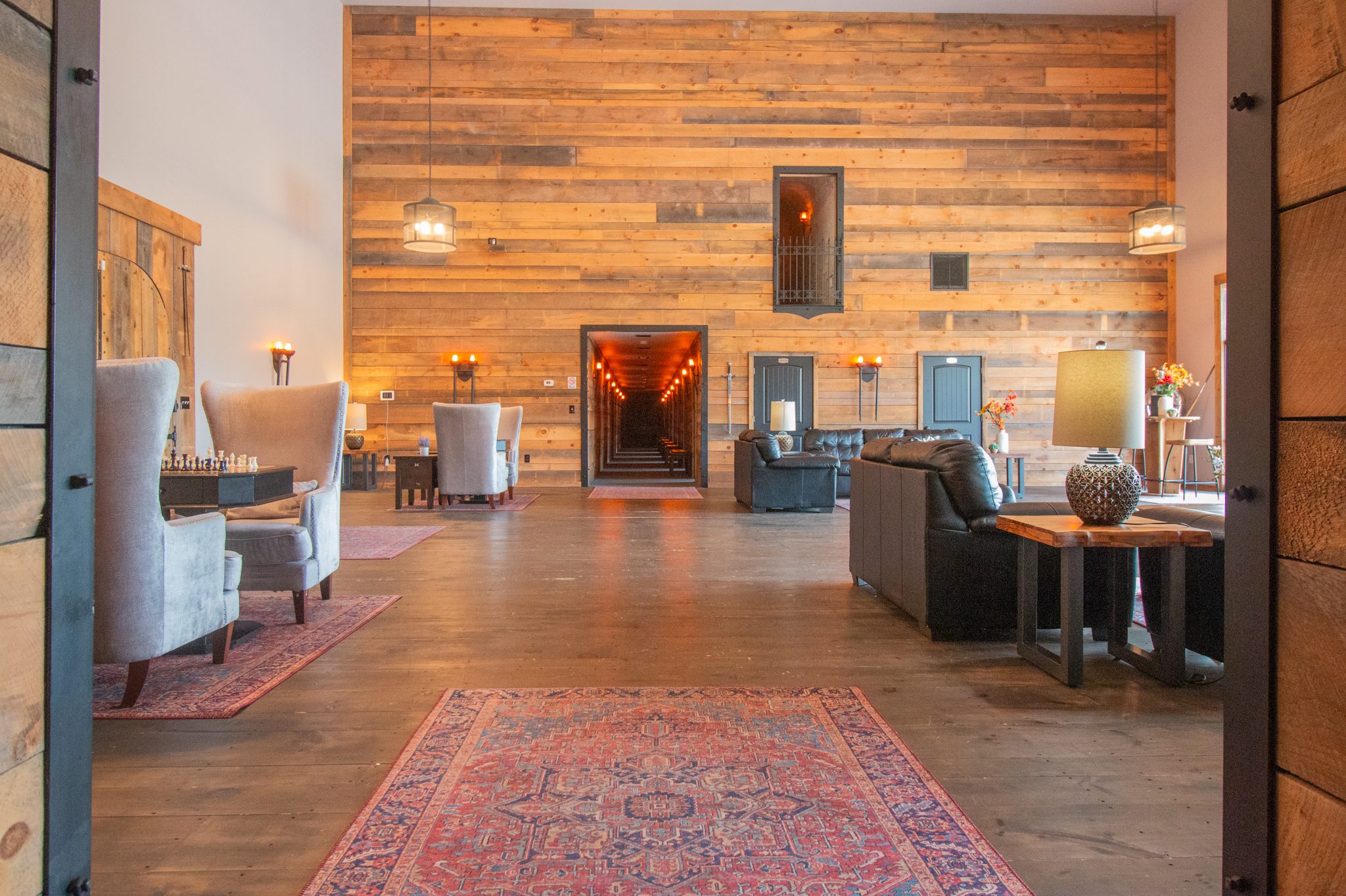 The Castle's foyer: timber-clad walls, armchairs and a rug, and a lit doorway through to the far side