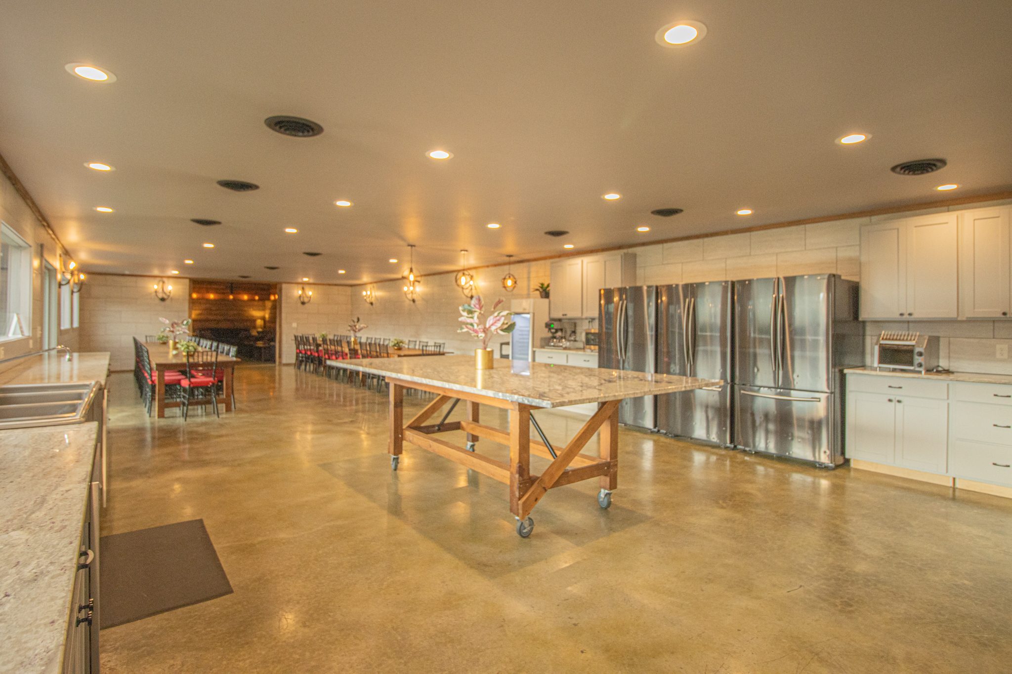The kitchen: a long island, white cabinets and a wall of steel refrigerators