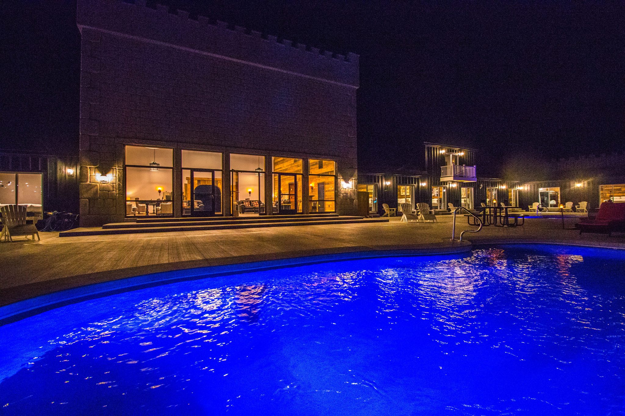 A pool lit blue at night, the lit windows of the Castle behind it
