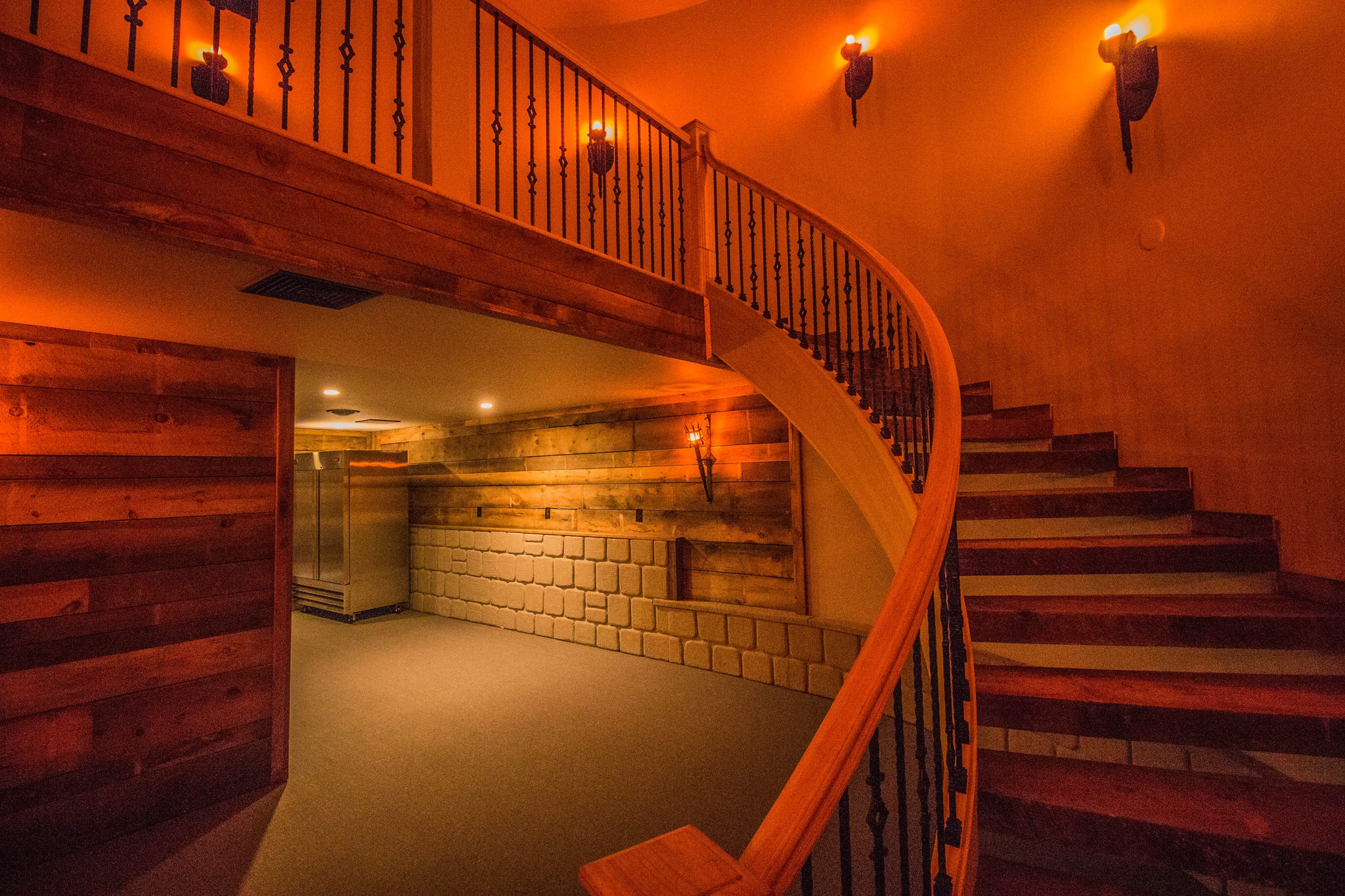 A curving timber staircase lit by wall torches