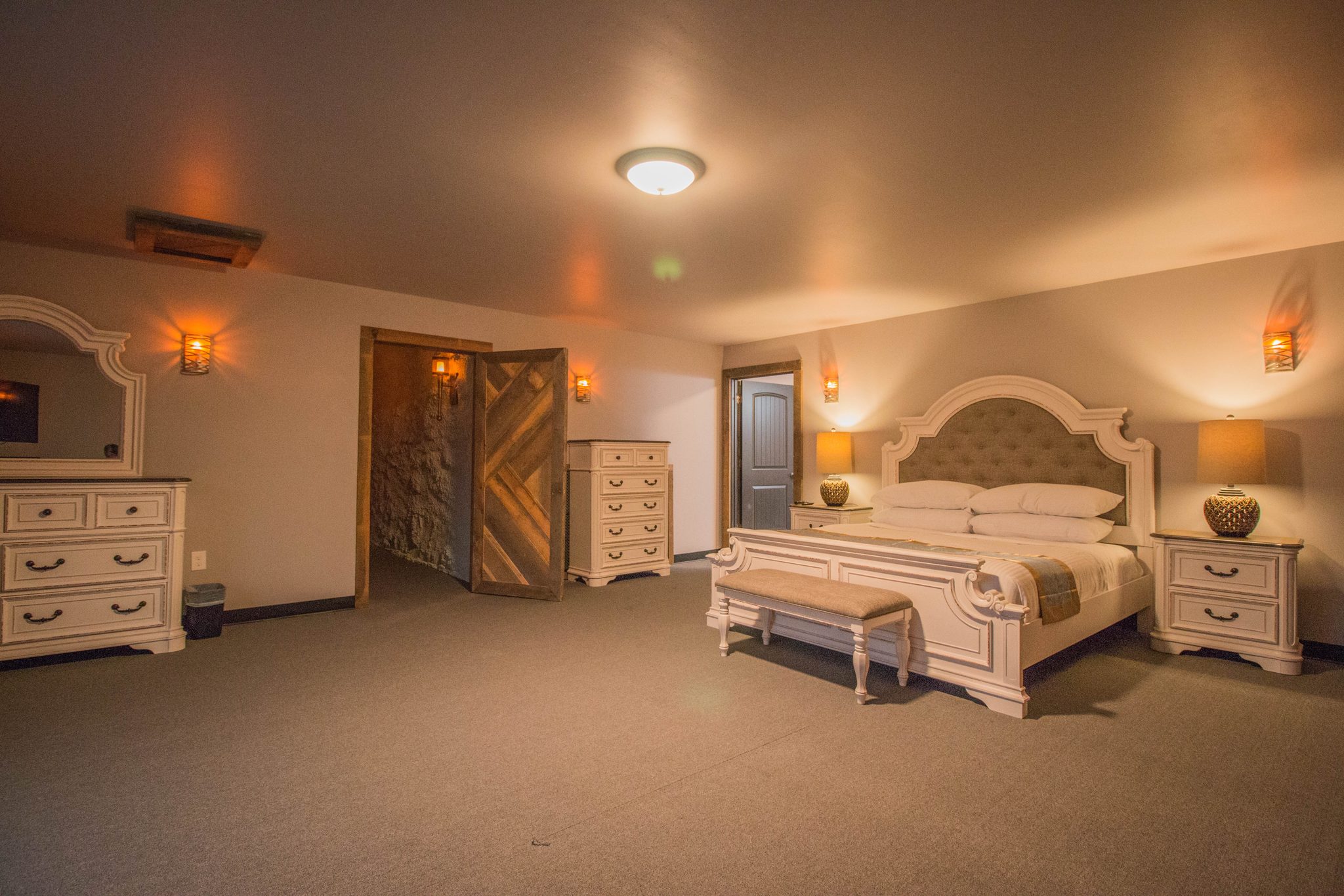 Tower Suite 1: a king bed with an upholstered headboard, a dresser and an arched timber door