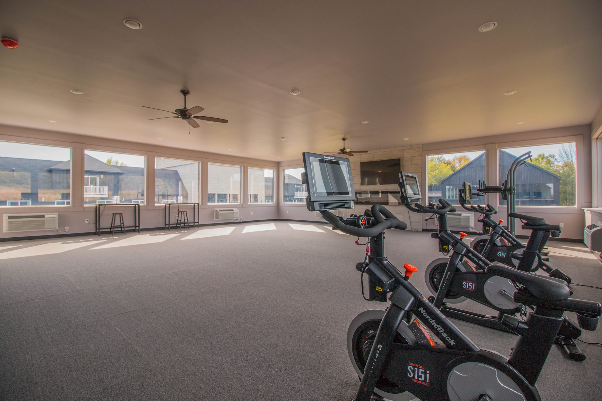 The yoga room: grey carpet, windows on three sides and a row of spin bikes