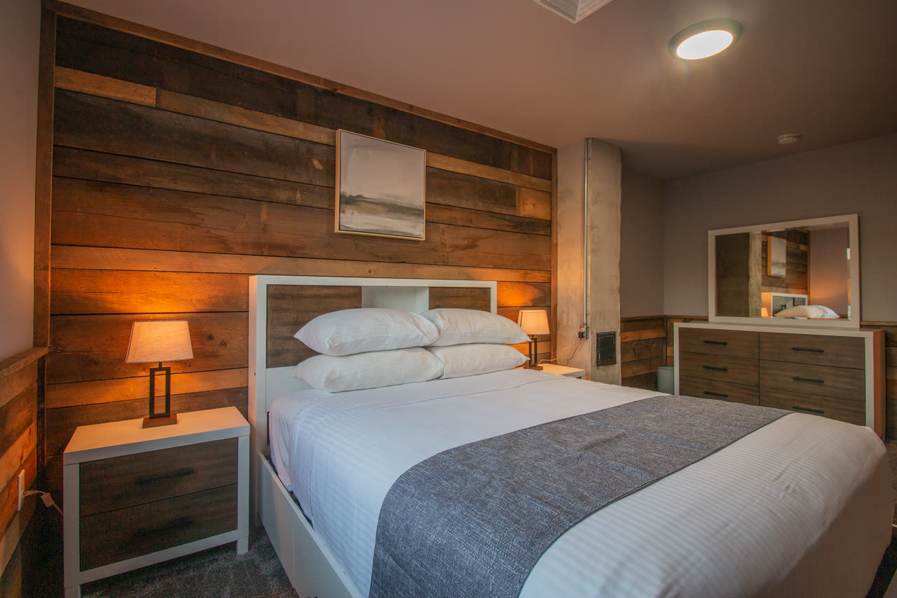 Bedroom 5, a queen bed against a reclaimed timber wall with a window onto the trees