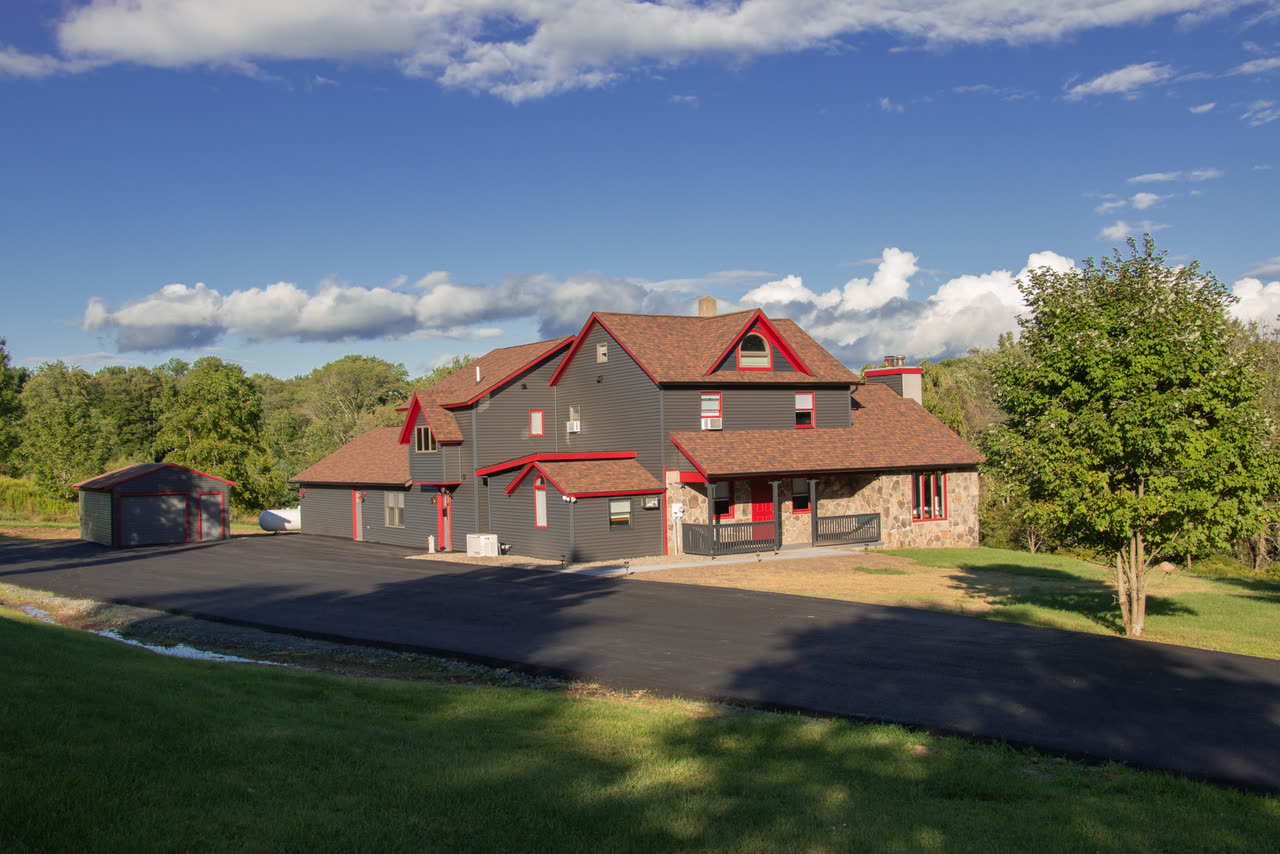 The Farmhouse from the drive, grey clapboard with red trim