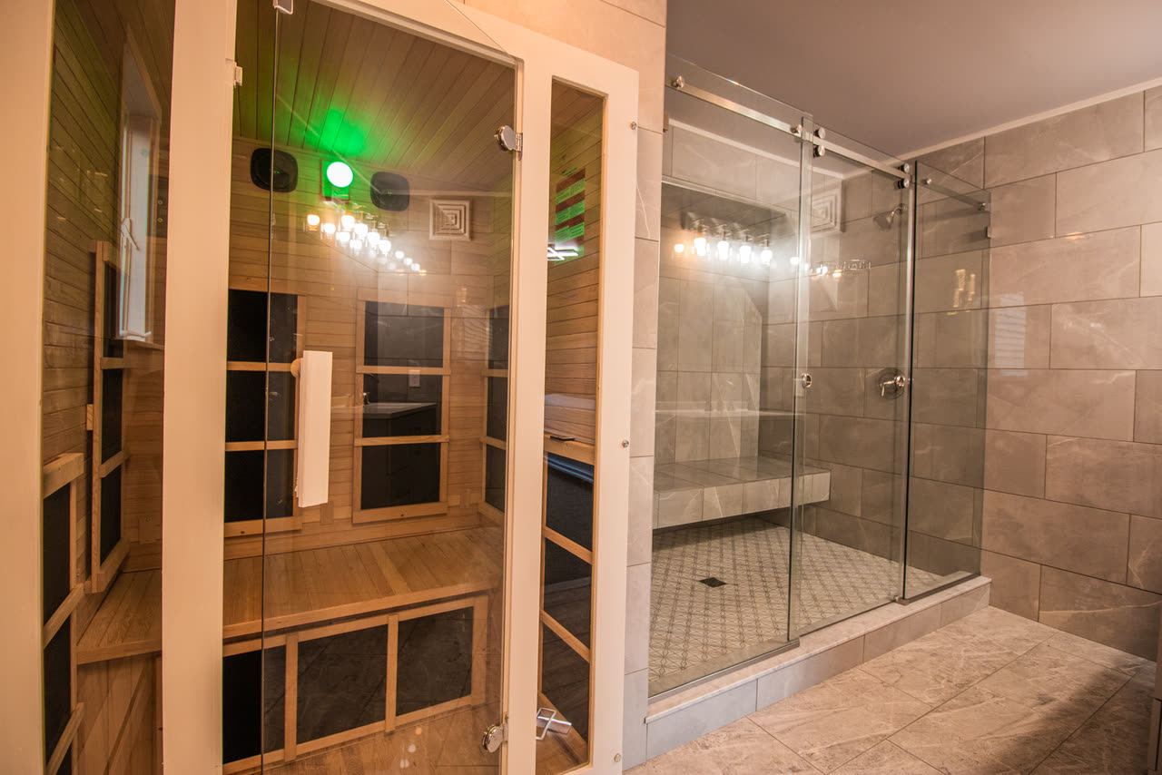 The cedar-lined sauna behind its glass door, next to a walk-in tiled shower, off the master bath