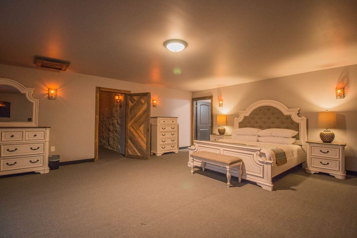 Tower Suite 1: a king bed with an upholstered headboard, a dresser and an arched timber door