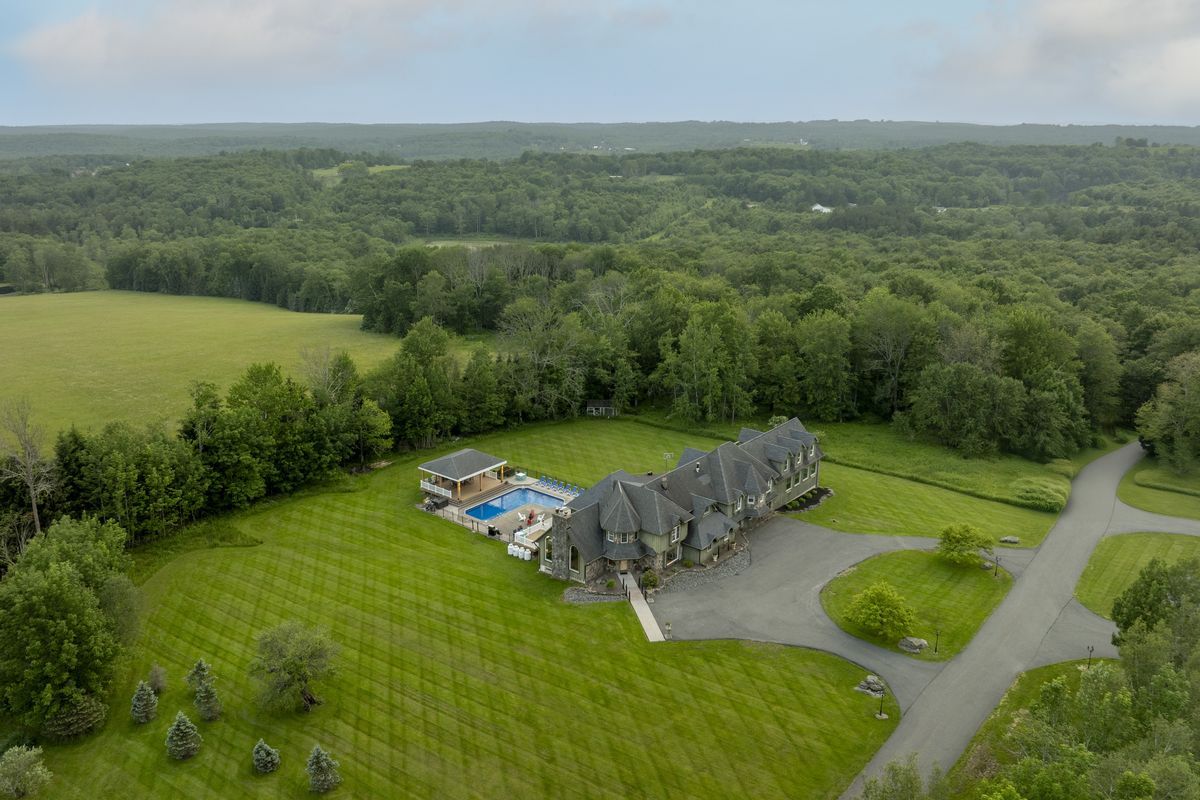 The Mansion from the air, its pool and covered pavilion beside it and open fields and woodland beyond