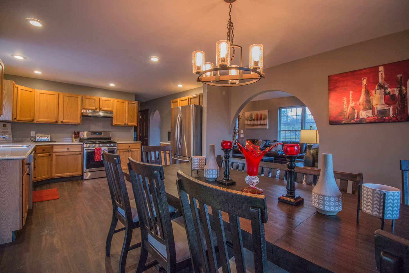 The dining table under an iron chandelier, laid for eight with the kitchen open behind it