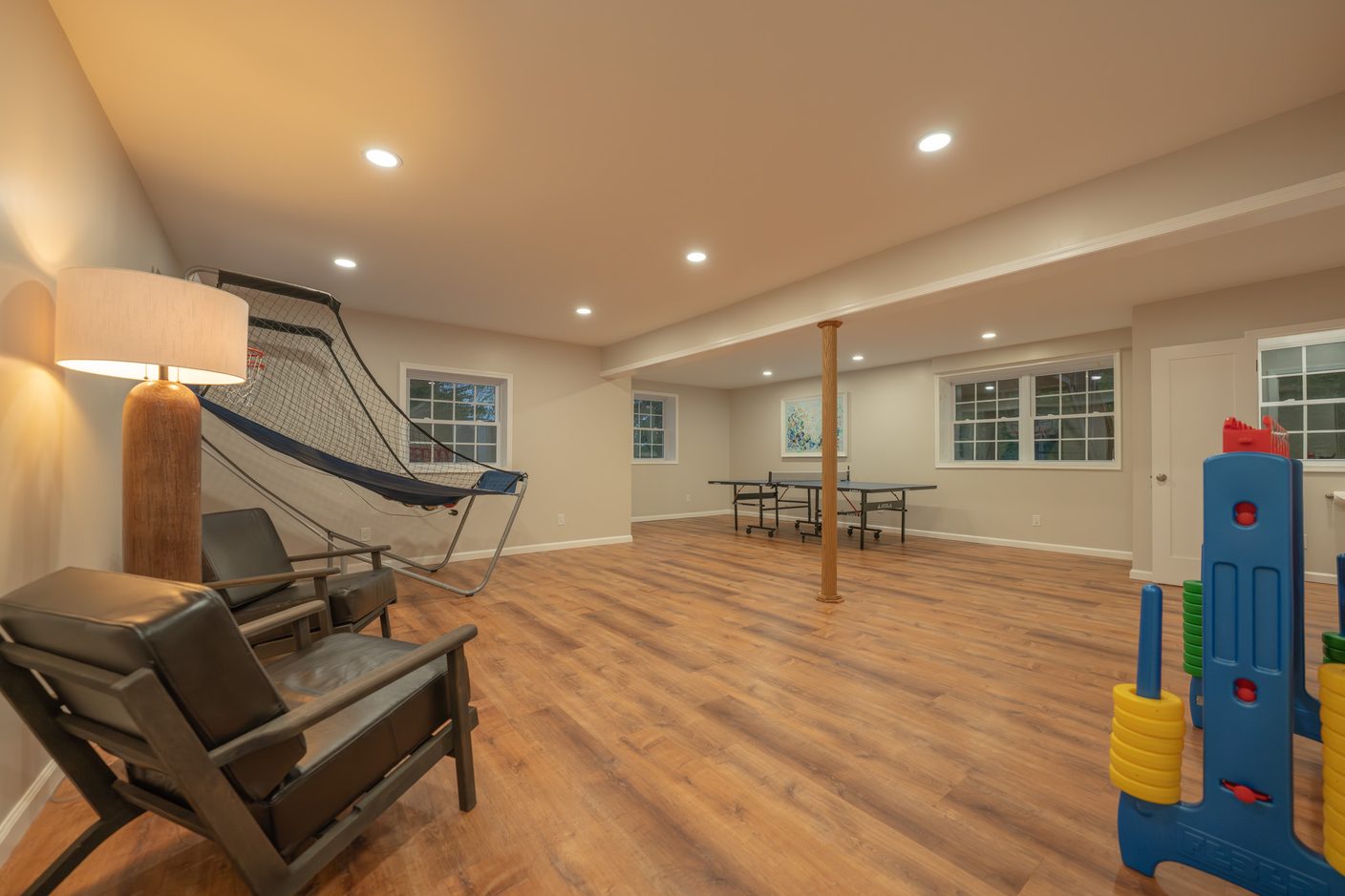 The games room downstairs, an arcade basketball hoop against one wall and a ping pong table under the windows