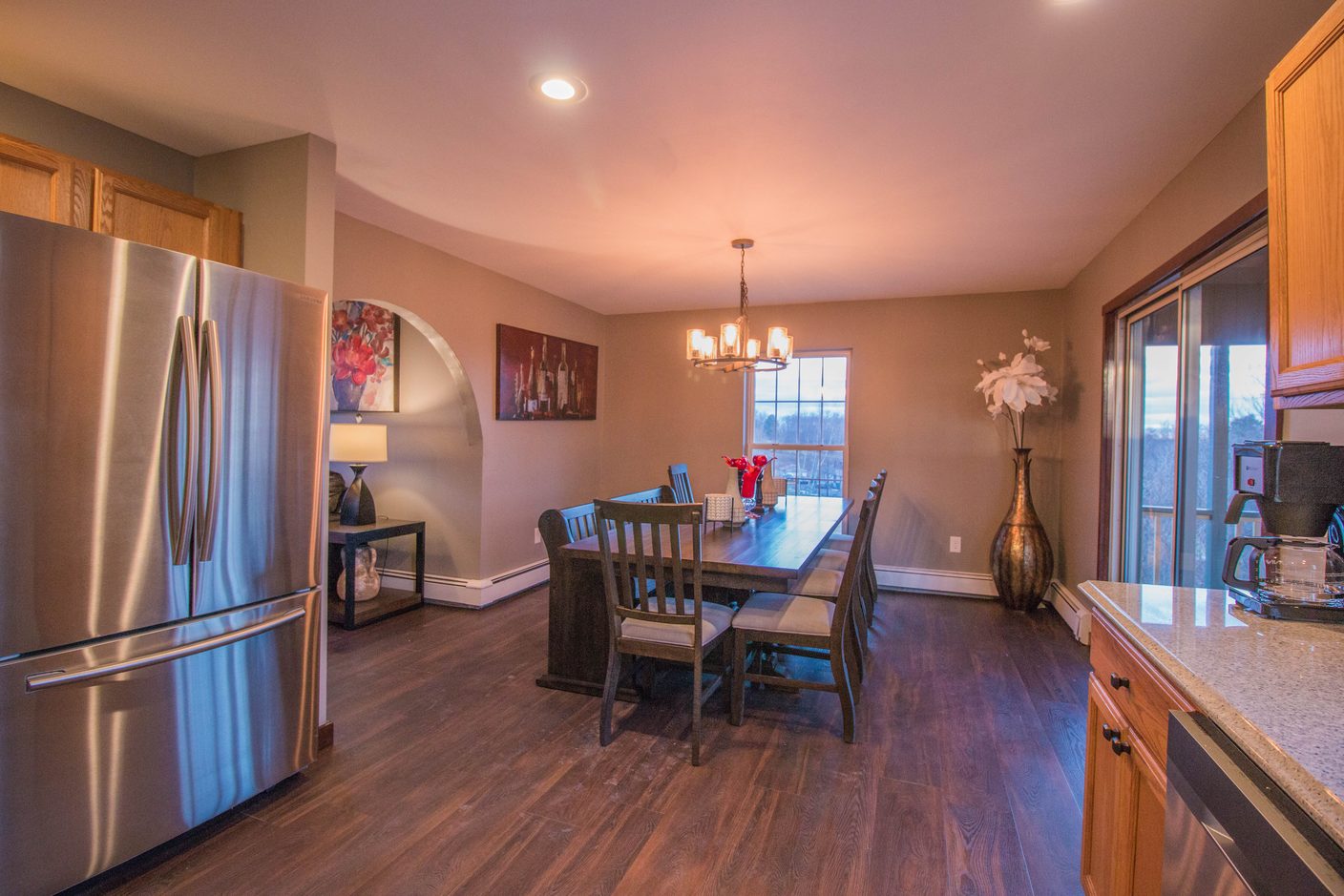 The kitchen looking through to the dining end, a tall refrigerator on the left and the table laid beyond the arch