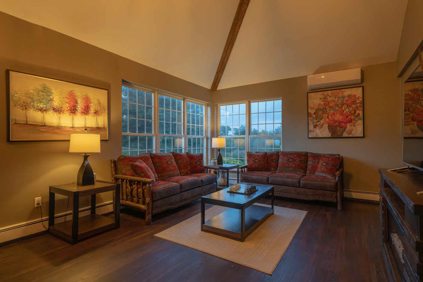The loft under the roof beams, long chairs facing the windows and a wall of framed prints