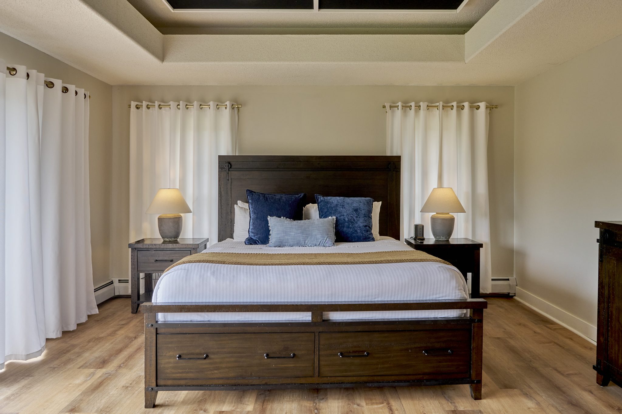 The master bedroom with a king bed, a coffered dark ceiling and doors onto a balcony