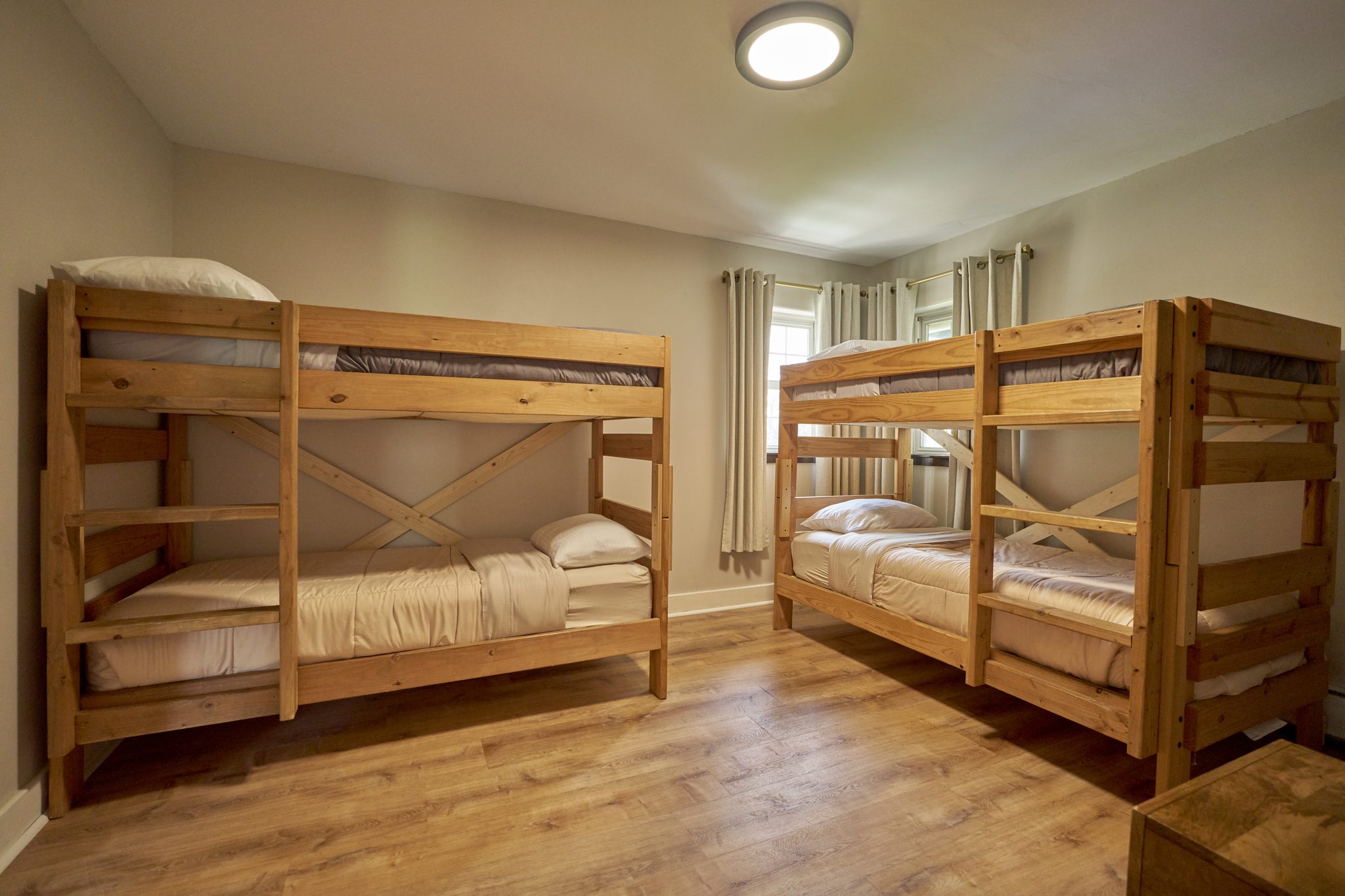 A bedroom with two wooden bunk beds against opposite walls