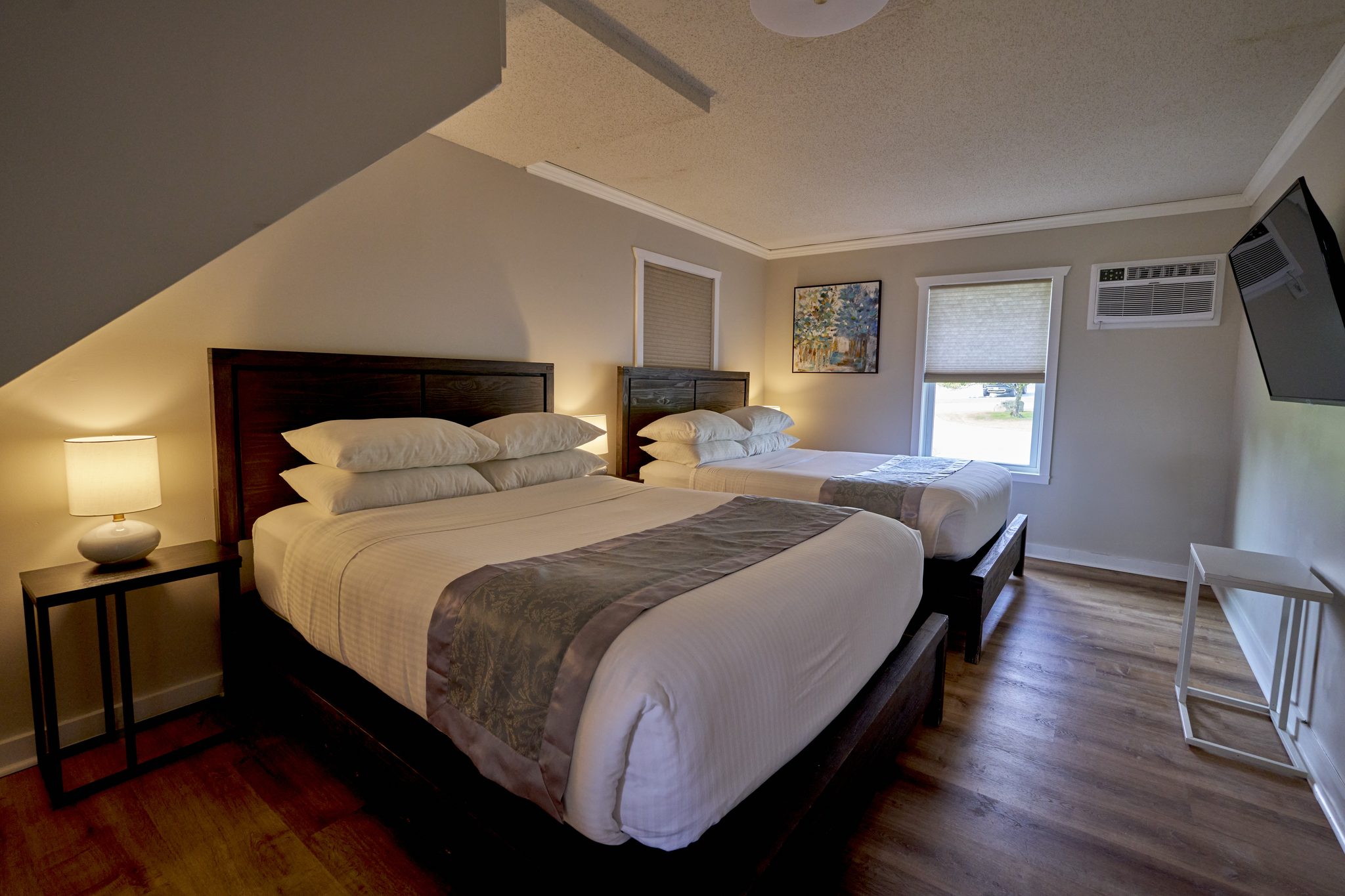 A bedroom with two queen beds side by side under a sloped ceiling