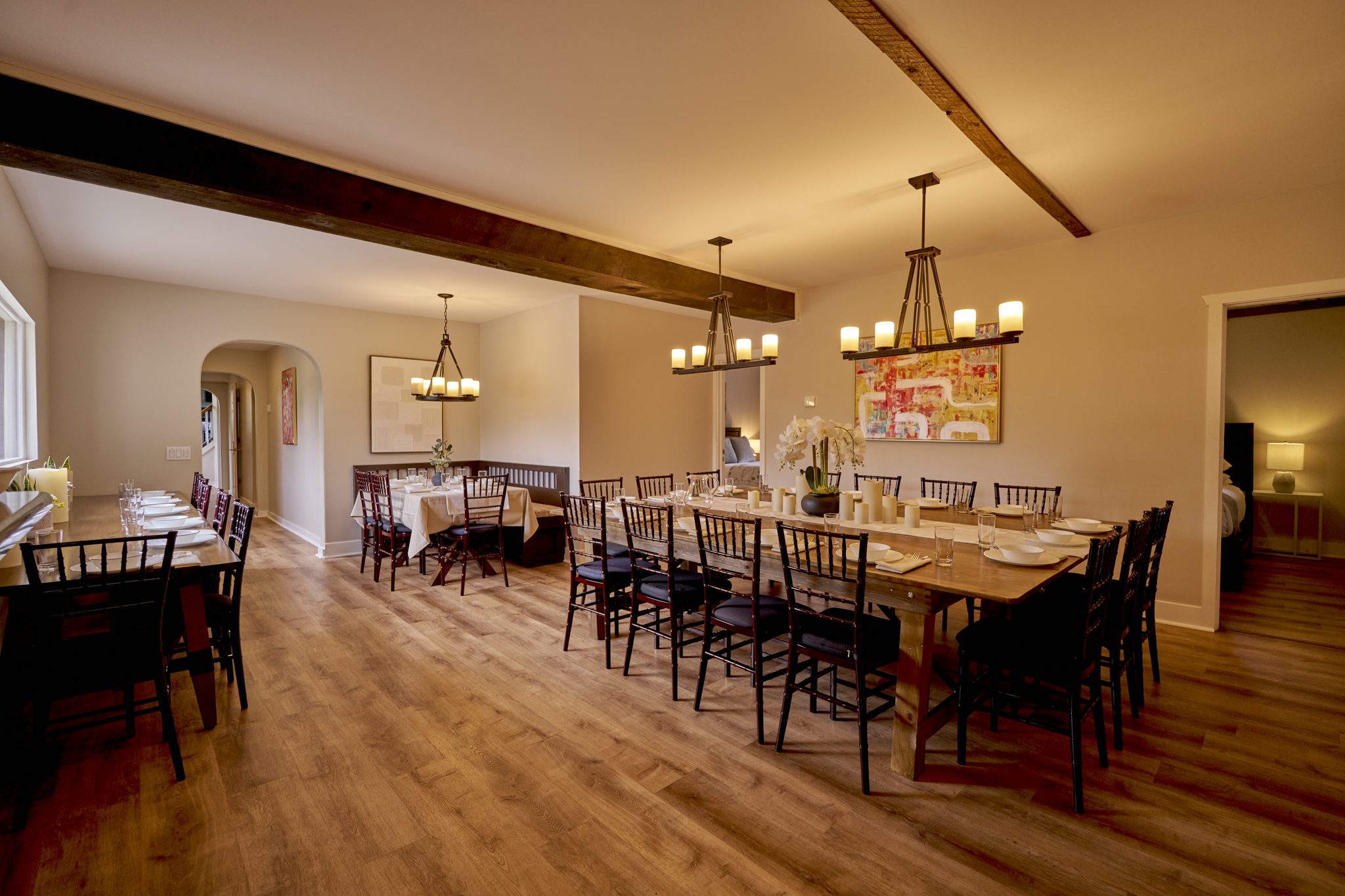 The Mansion's dining room, two long tables under iron chandeliers and exposed beams