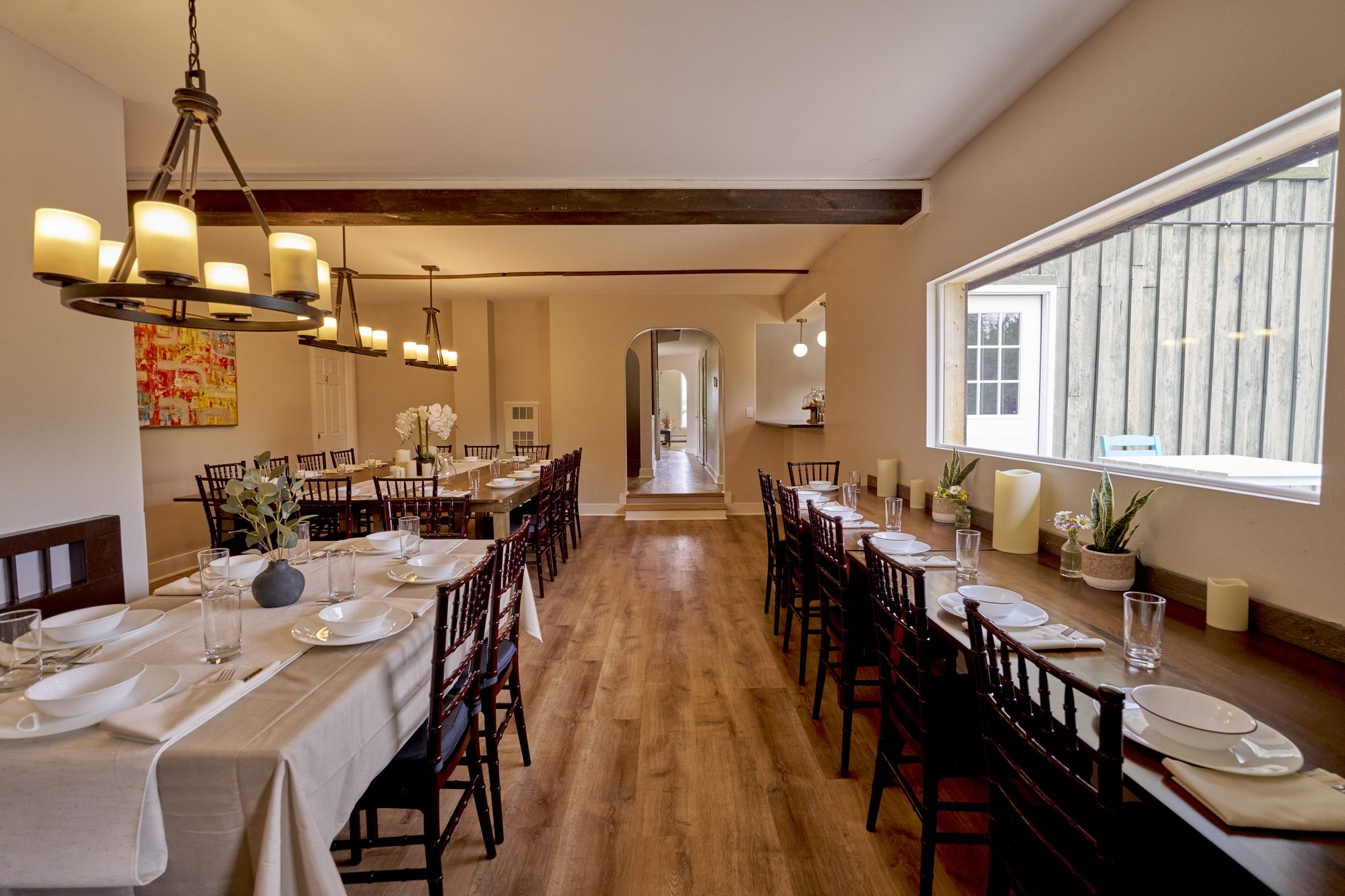 The dining room laid with white cloths and place settings, daylight from the windows along one side