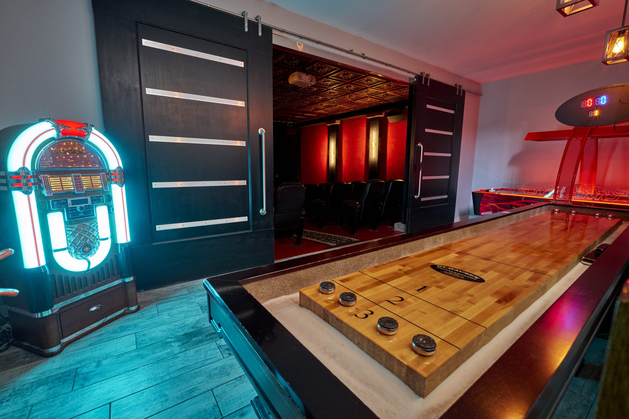An air hockey table glowing red under neon in the game room