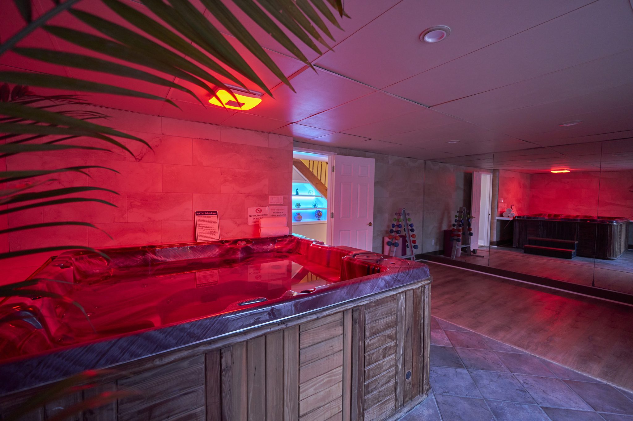 An indoor hot tub in a room lit deep red, steps up to the rim