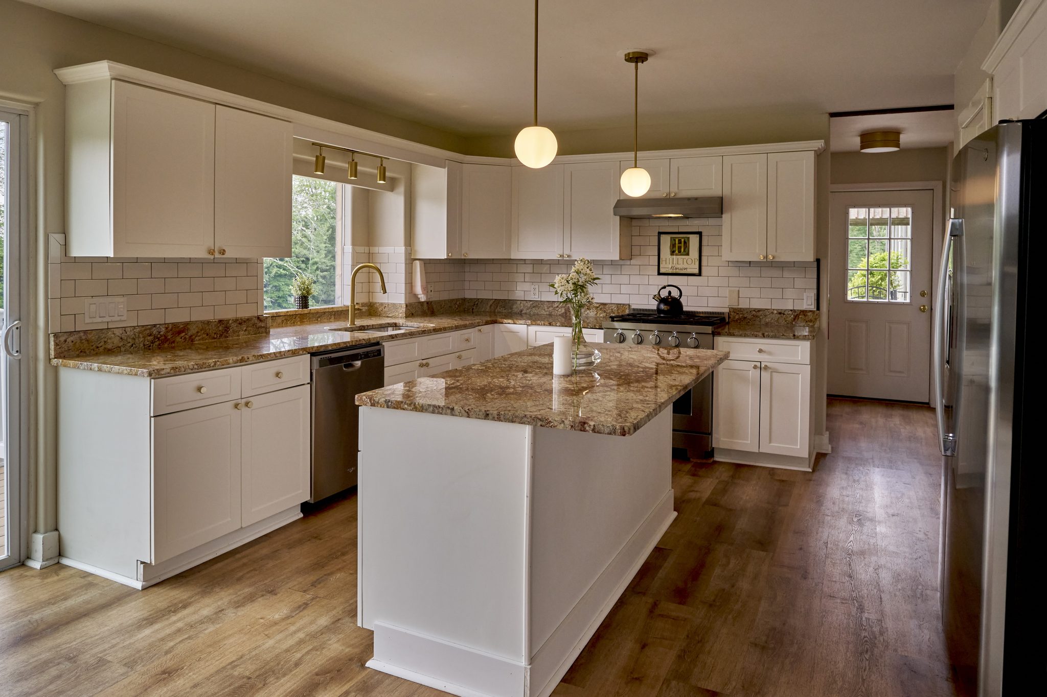 The Mansion's main kitchen, white cabinets and a granite island under recessed lights