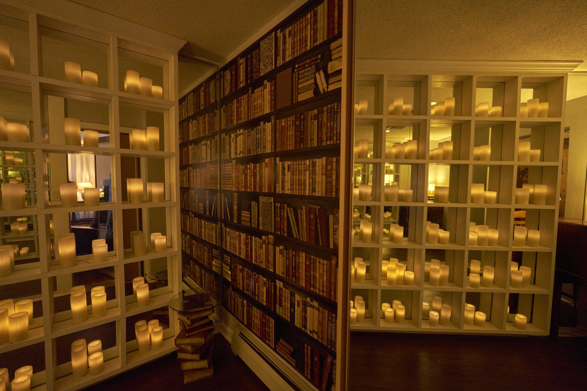 Floor-to-ceiling bookshelves lit from within, filling a narrow room