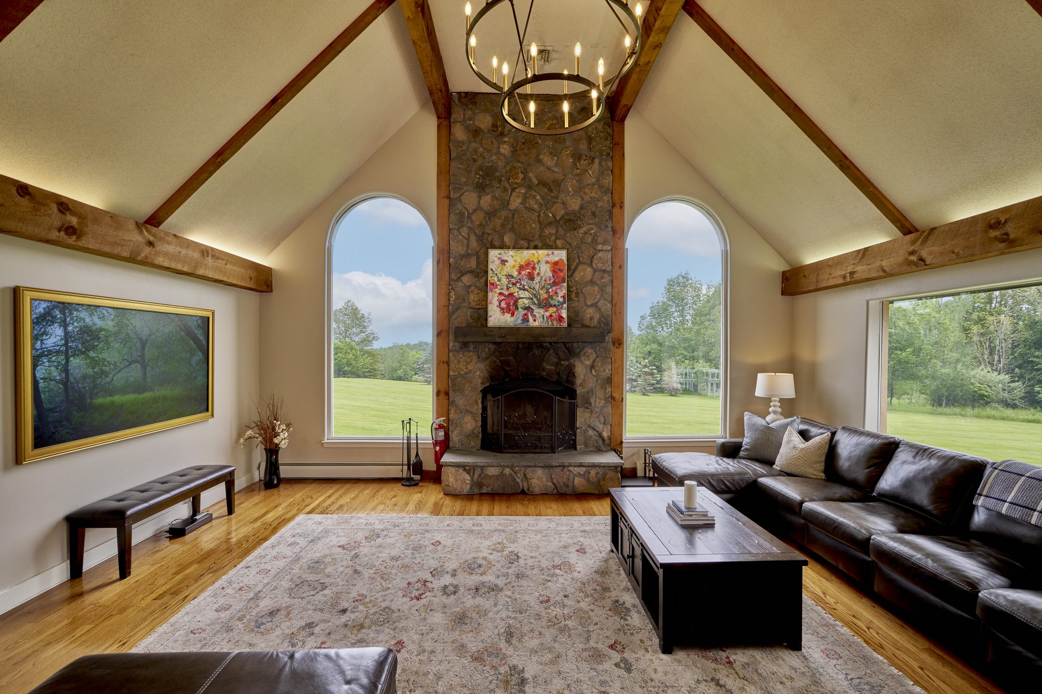 The living room's stone fireplace rising the full height of the vaulted ceiling, leather sofas on a pale rug