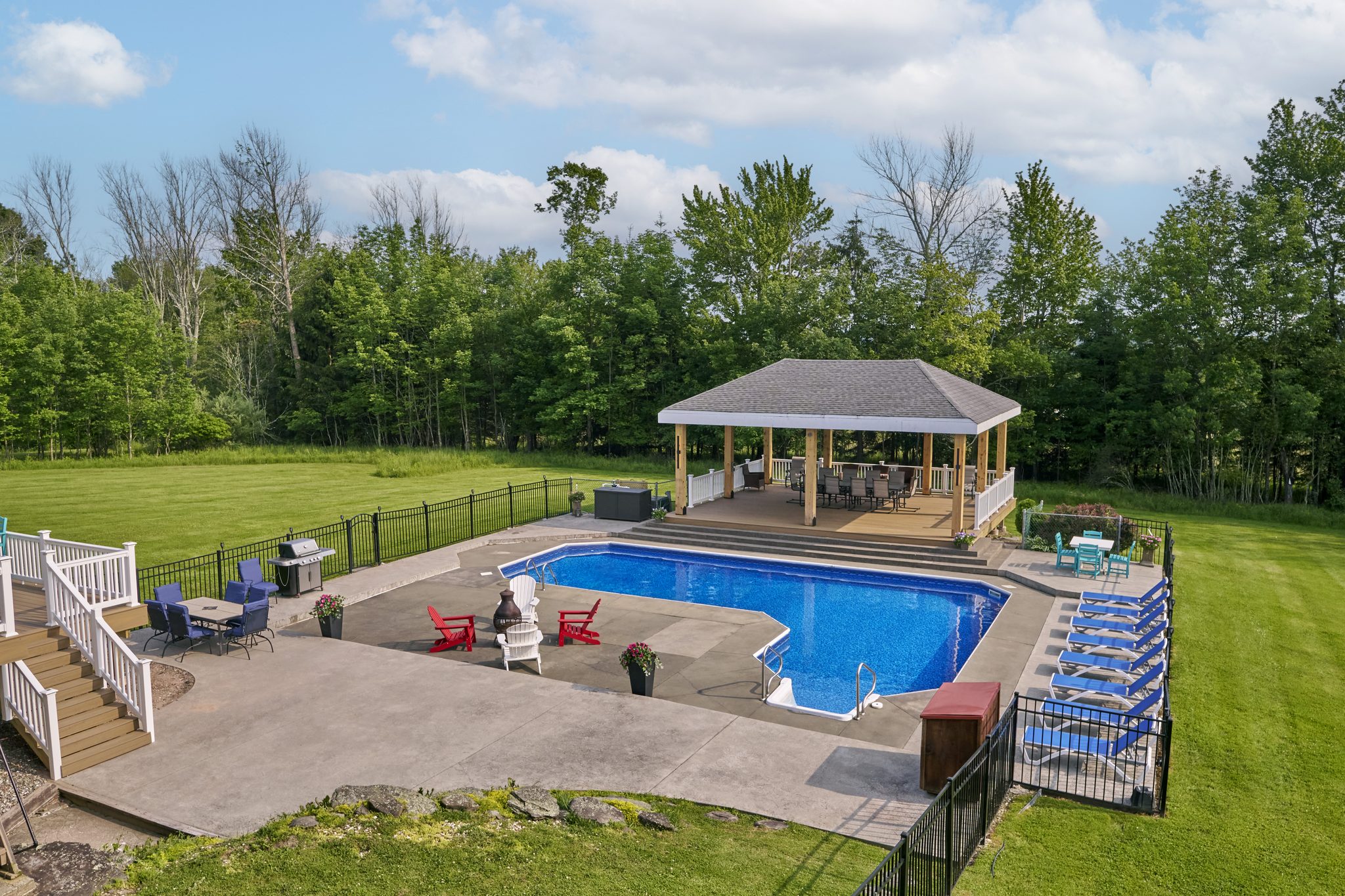 The Mansion's outdoor pool on a lawn, loungers along one side and a covered gazebo beyond