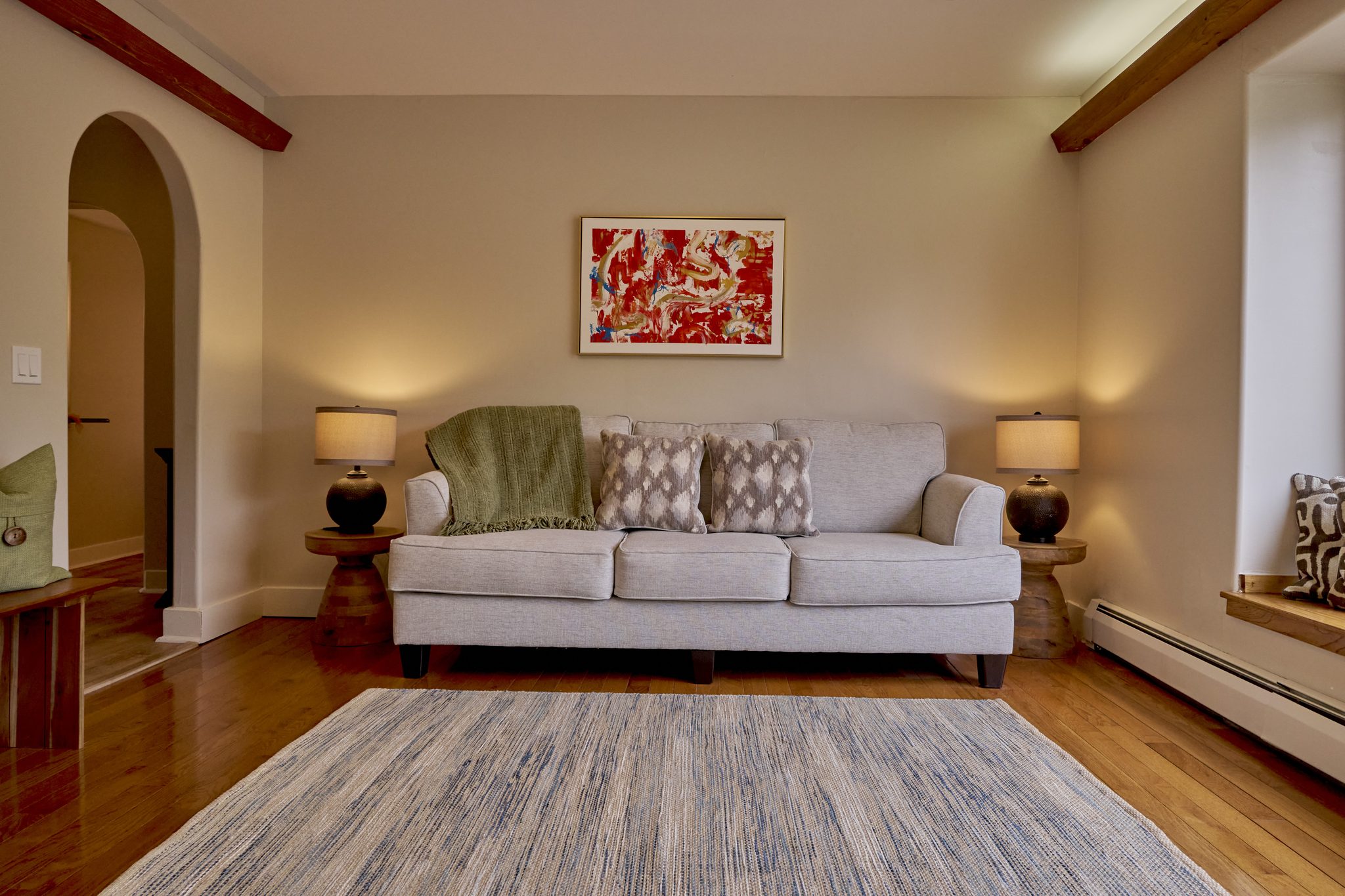 A quiet sitting room with a pale sofa under an arched doorway